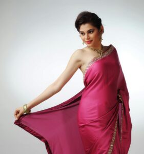 Elegant Indian woman posing in a vibrant pink sari, showcasing traditional fashion and jewelry.